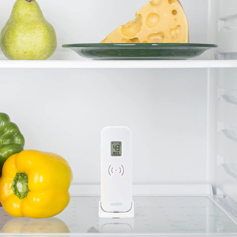 Front view of white La Crosse Technology wireless refrigerator/freezer thermometer with magnetic back on a fridge shelf.