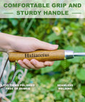 Hand holding Beefy Stainless Steel Bend Proof Garden Trowel With Comfortable Wood Handle against green garden background.