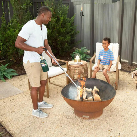 Man using Self Igniting Outdoor Torch, 20,000 BTU High Output Flame, 36 Inch Handle on firewood in outdoor fire pit