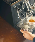 Rock Solid Dual Boiler Espresso Machine Bundle With Precision Grinder And Pid brewing espresso with milk steaming in stainless pitcher.
