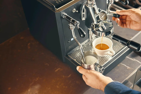 Rock Solid Dual Boiler Espresso Machine Bundle With Precision Grinder And Pid brewing espresso with milk steaming in stainless pitcher.