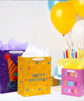 Three birthday gift bags with ribbon handles and tissue paper, assorted sizes including extra large, large, and medium