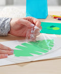 Using Big League Permanent Adhesive Refill Cartridge to apply a green leaf cutout on white paper for crafting.