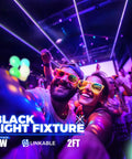 Party scene lit by UV LED Blacklight Bar 9W 2Ft T5 Integrated Fixture, glasses glowing under black light, crowd dancing.