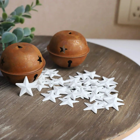 White Mini Metal Barn Stars Set of 27 for Crafts Handcrafted 1 Inch Metal Ornaments with Antique Finish displayed on a wooden surface