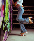Person wearing jeans with quad skates showing 4 Piece PU Double Row Roller Skate Wheels With Bearings For Quad Skating in action.