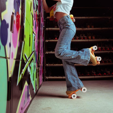 Person wearing jeans with quad skates showing 4 Piece PU Double Row Roller Skate Wheels With Bearings For Quad Skating in action.
