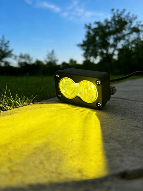Ultra Bright 20W 6500K Baja Style LED Headlight Bar casting yellow light outdoors, showcasing IP68 waterproof, rugged design.