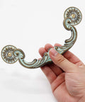 Person holding Four Piece 6 Inch Center Hole Pull Handles Set In Zinc Alloy Rustic Vintage Drop Down Bail Swing Dresser Pulls.