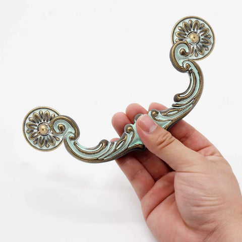 Person holding Four Piece 6 Inch Center Hole Pull Handles Set In Zinc Alloy Rustic Vintage Drop Down Bail Swing Dresser Pulls.