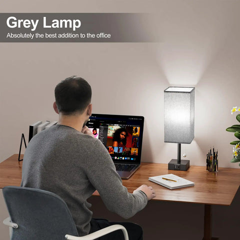 Gray Bedside Lamp With Dual USB Ports USB C And USB A on desk, charging laptop, soft glow, wood surface, bulb not included