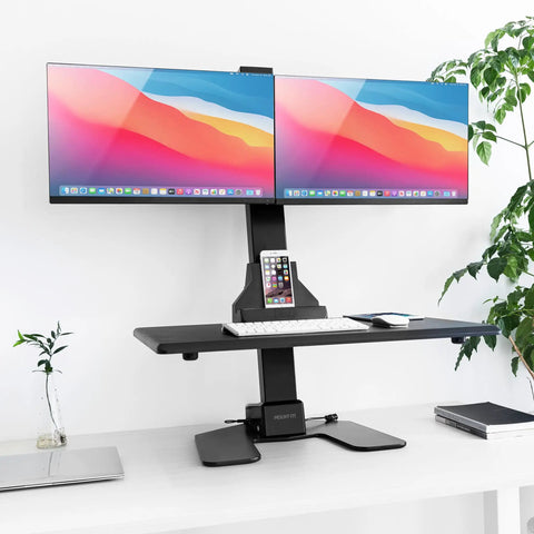 Electric Dual Monitor Sit Stand Desk Converter with 28 Inch Base Height Adjustable Desktop Riser holding two 32-inch screens