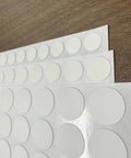 White Screw Hole Cover Set Including 290 Pieces In Three Sizes 12mm 15mm And 21mm Self Adhesive PVC Caps on a wooden surface