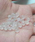 Close-up of clear earring backs in hand, representing pacifier-grade soft TPE safety earring backs.