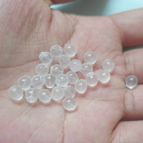 Close-up of clear earring backs in hand, representing pacifier-grade soft TPE safety earring backs.