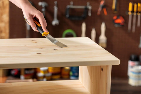 Applying stainable wood filler for cracks and dings 16 oz paintable latex formula on wooden surface in workshop