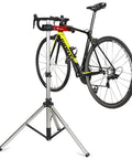 Bike Repair Stand With 360 Degree Swivel Clamp Adjustable Foldable Work Stand Lightweight Aluminum Floor Station 85 Lbs Max Capacity Tripod Base Quick Release Perfect For DIY Home Mechanics holding a bicycle