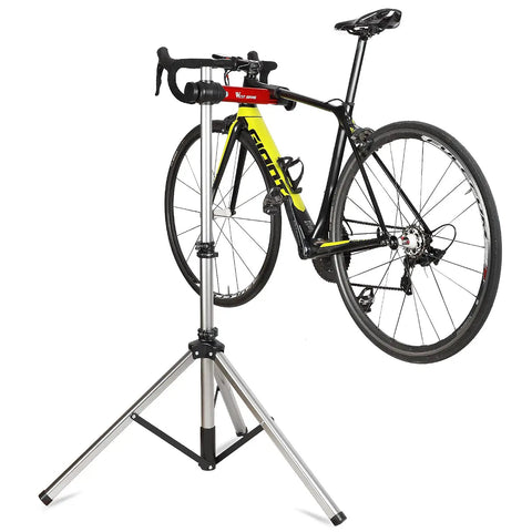 Bike Repair Stand With 360 Degree Swivel Clamp Adjustable Foldable Work Stand Lightweight Aluminum Floor Station 85 Lbs Max Capacity Tripod Base Quick Release Perfect For DIY Home Mechanics holding a bicycle