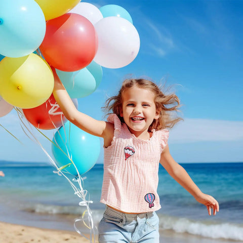 Child wearing 13 Piece Hot Air Balloon Iron On Patches Set With Colorful Embroidered Appliques For Clothes on beach