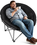 Man sitting in XXL Folding Round Camping Chair With Super Cushioned Padded Seat For All Day Comfort Heavy Duty Frame Supports Up To 400 Lbs