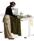 Person sewing on Electric Adjustable Workbench With 55 By 28 Inch Desk And Smooth Height Adjustment From 28 To 46 Inches Four Memory Presets