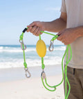 Person holding a Marine Tow Line With Pulley Shock Absorb Bungee Dock Line Stretchable Rope in yellow and green on a beach