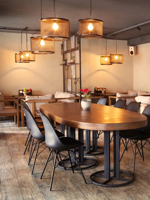 Cozy restaurant interior with wooden table, black chairs, pendant lights, and ambient decor.