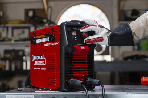 Person using Weld Pak 225i Dual Voltage Stick and TIG Welder 120V 230V, 10 to 225 Amp Output, Lightweight 20 lb Inverter in a garage.
