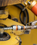 THINKWORK 8000 PSI grease gun kit with pistol grip on yellow industrial machinery; knurled coupling and spring visible.