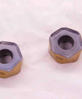 Two Pack New H1200 HXCU 0606 HPR IC830 AlTiN And TiN Coated Carbide Inserts with hexagonal design on white background
