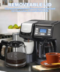 Replacement 12-cup glass coffee carafe with black handle, front view beside the coffee maker's own carafe.