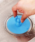 Hand holding a blue Shape Floor Drain Plug, Shower Bathtub Drain Covers, Green, in stainless steel sink.