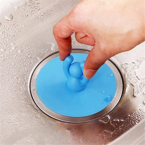 Hand holding a blue Shape Floor Drain Plug, Shower Bathtub Drain Covers, Green, in stainless steel sink.