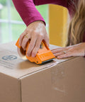 Person using Tough As Nails Clear Packing Tape For Moving And Storage 2.83 Inch By 30 Yard Two Rolls on a cardboard box.