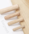 Four wood dowel pins of different sizes next to a wooden board from Wood Dowel Pins Kit 505 Pcs Four Sizes 1/4 In 5/16 In 3/8 In 1/2 In Straight Grooved Dowel Pins With Center Point Cylindrical Wood Dowels For Furniture Making Assortment Set.