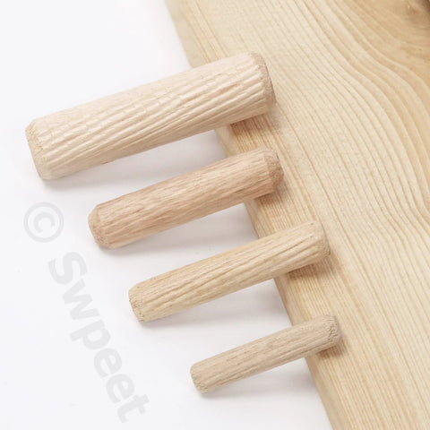 Four wood dowel pins of different sizes next to a wooden board from Wood Dowel Pins Kit 505 Pcs Four Sizes 1/4 In 5/16 In 3/8 In 1/2 In Straight Grooved Dowel Pins With Center Point Cylindrical Wood Dowels For Furniture Making Assortment Set.