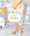 Woman holding 13 Inch Large Baby Gift Bag For Baby Shower Or Birthday with sturdy handle and tissue paper, vibrant green unisex design.