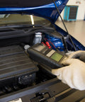 Mechanic using diagnostic scanner on car engine in workshop