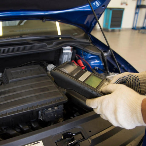 Mechanic using diagnostic scanner on car engine in workshop
