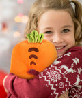 Child hugging carrot-shaped plush pillow with embroidered details and green leaves