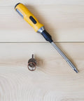 Screwdriver next to 80 Piece Retro Mini Cabinet Pull Handles Rings With Drop Bail Knobs For Small Furniture on wood surface.