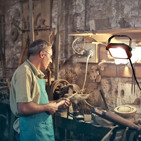 Man in workshop using 1100 Lumen LED Work Light With Tiltable Head Red Finish 4000K Cool White 2-In-1 Rotating Stand And Handle
