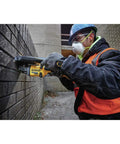 Worker using FlexVolt 60V Max Cordless Angle Grinder With Kickback Brake for grinding bricks; 4.5-6 inch, heavy-duty tool in action.
