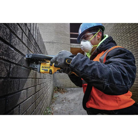 Worker using FlexVolt 60V Max Cordless Angle Grinder With Kickback Brake for grinding bricks; 4.5-6 inch, heavy-duty tool in action.