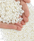 Butter Smooth Imitation Pearl Spacer Beads Kit With 10 Boxes Of 3 To 14 Mm assorted white pearl beads held in hand.