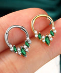 Silver and gold V-shape septum rings with green and white stones on a finger for Blue CZ V Shape Septum Ring 16G Stainless Steel Helix Daith Piercing Jewelry For Everyday Wear Dope Style Lightweight And Comfortable Hypoallergenic Nose Ring
