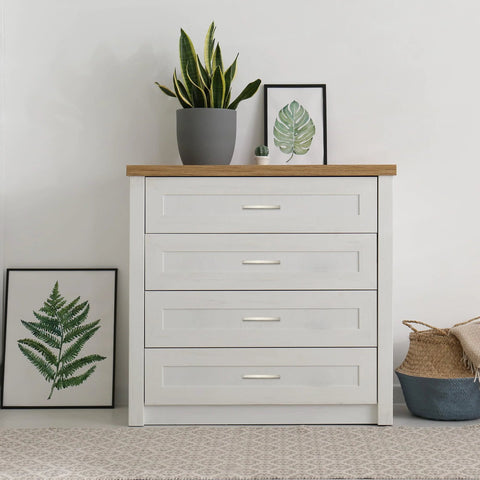 White dresser with four drawers and brushed nickel cabinet pulls, decorated with plants and wall art, modern bedroom decor