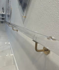 Clear Acrylic Stair Handrail With Rock Solid Gold Wall Brackets And Heavy Duty Stainless Supports Non Slip Grip Banister For Modern Homes No Sweat Install Indoor Outdoor Railing mounted on a wall, showcasing modern design.