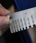 Close-up of Round Dual Sided Metal Sheet Gauge and Thickness Gauge being used, showing measurement markings on stainless steel.