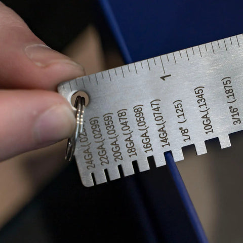 Close-up of Round Dual Sided Metal Sheet Gauge and Thickness Gauge being used, showing measurement markings on stainless steel.